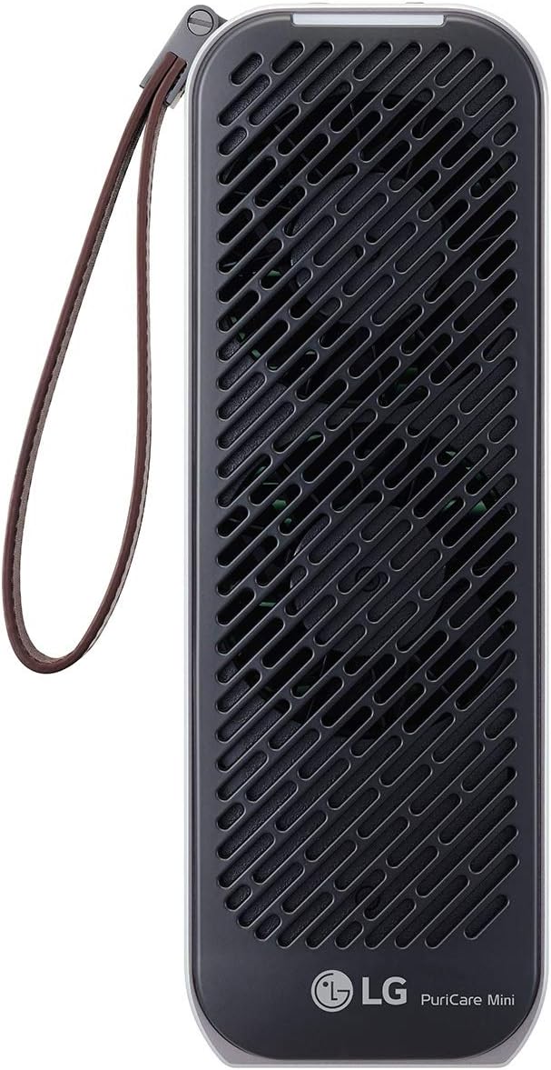A compact LG PuriCare Mini air purifier with a sleek black grille design covering the front and a silver frame. It features a leather wrist strap attached to the side for portability. The LG logo and "PuriCare Mini" branding are displayed at the bottom, emphasizing its modern and minimalist design.