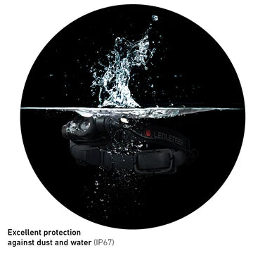 A black LED Lenser headlamp partially submerged in water, with a splash effect captured at the water's surface. The image, set against a black circular background, emphasizes the headlamp's IP67 rating for excellent protection against dust and water. The LED Lenser logo is visible on the headlamp's strap. The caption below the image reads, "Excellent protection against dust and water (IP67)."