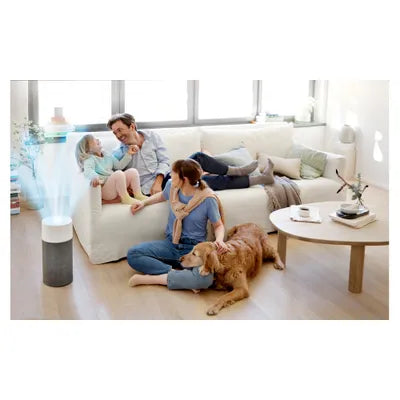 A family sits comfortably in a bright, modern living room with a dog, while a cylindrical air purifier emits clean air nearby, enhancing indoor air quality for a healthier home environment.
