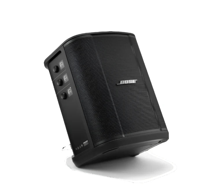 Angled front view of a black Bose speaker, showcasing its sleek, curved design. The front grille prominently displays the Bose logo. The side panel features three knobs for adjusting volume, treble, and bass, each with corresponding icons and digital displays. The speaker is tilted, emphasizing its modern and functional design, with a focus on portability and ease of use.
