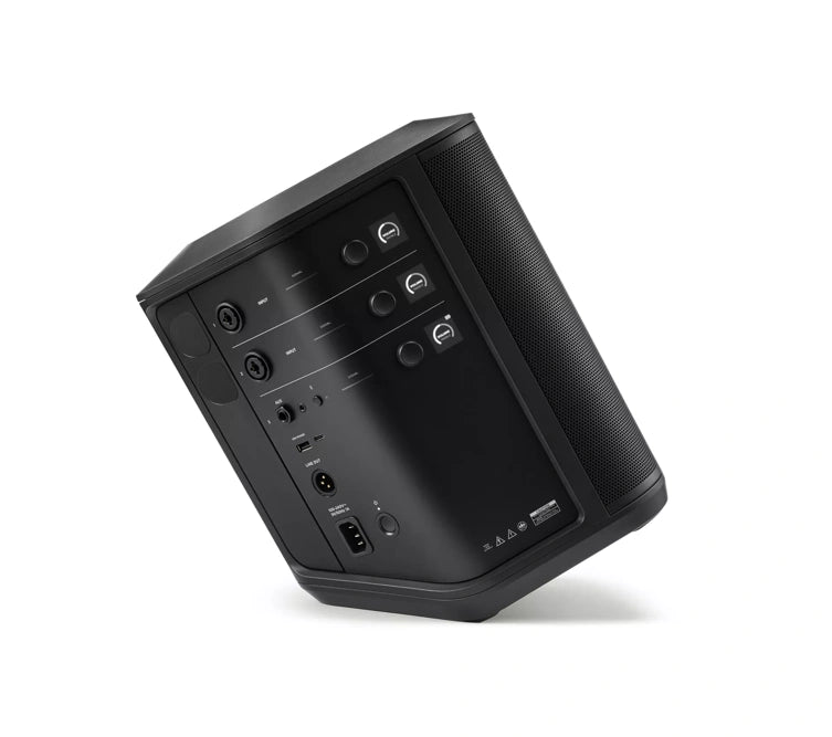 Angled side view of a black Bose speaker, showing its control panel and input/output ports. The control panel includes three knobs for adjusting volume, treble, and bass, each with corresponding digital displays. The input/output ports include two XLR/TRS combo jacks, a 3.5mm auxiliary input, a USB port, and a power input. The speaker is tilted to display all controls and connections clearly, emphasizing its sleek and functional design.