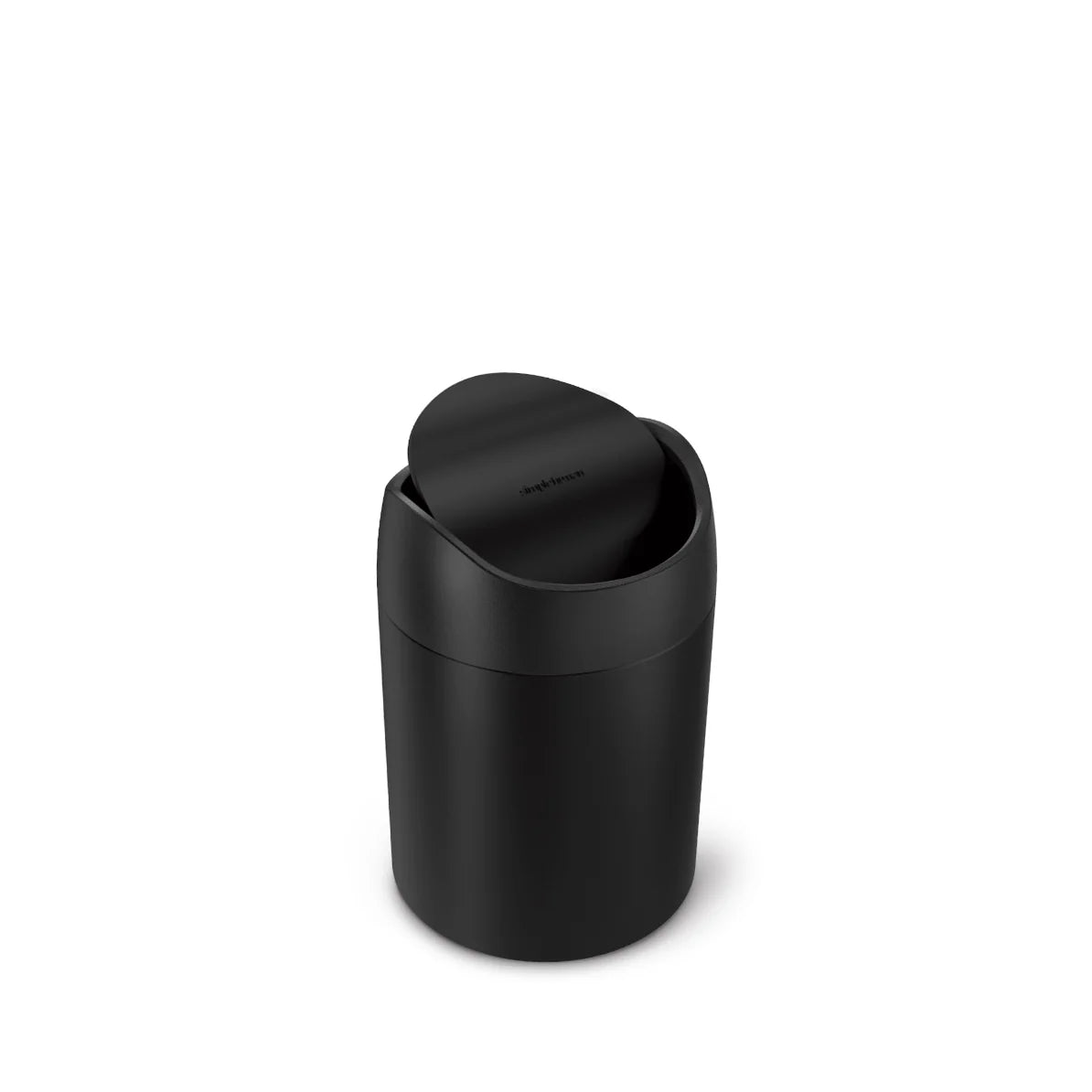 The image shows a Simplehuman mini round trash can with a swing lid, finished in matte black. The swing lid is slightly open, allowing a view of the interior while maintaining the trash can's sleek and minimalist design. The matte black finish gives it a modern and sophisticated look, ideal for small spaces such as bathroom countertops, vanities, or desks. The Simplehuman logo is subtly embossed on the swing lid, adding a touch of branding to the understated design. This trash can combines practicality with