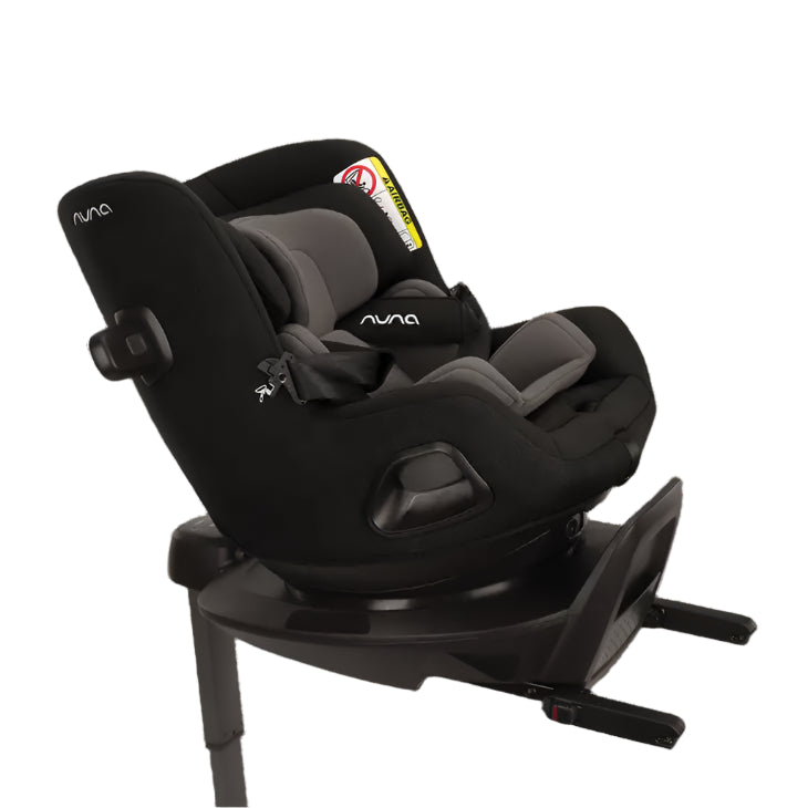 Angled side view of a Nuna convertible car seat in rear-facing reclined position, featuring padded grey inserts, five-point harness, support leg, and ISOFIX base with swivel mechanism for easy access.