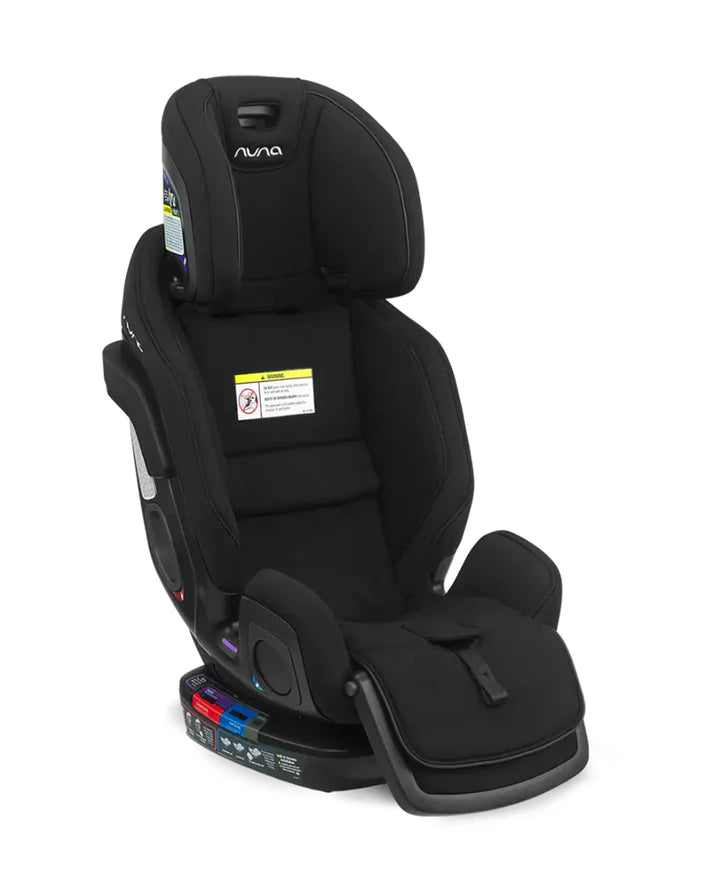 A black Nuna convertible car seat in booster mode, featuring a tall backrest, extended leg support, and no visible harness straps, designed for older children.