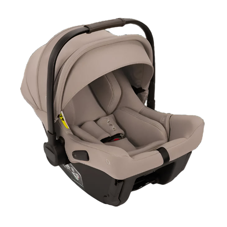 A beige Nuna infant car seat with a curved black handle, extended canopy, and five-point harness system, designed for rear-facing use and safety on the go.