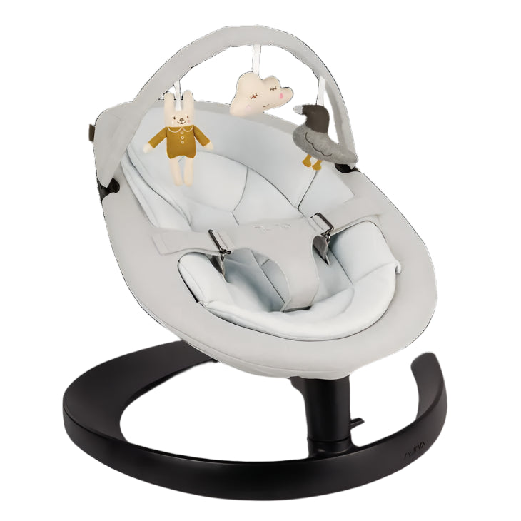 A modern baby rocker in soft white fabric with a dark base, featuring an overhead toy bar with a bunny, cloud, and bird plush toy hanging for entertainment.