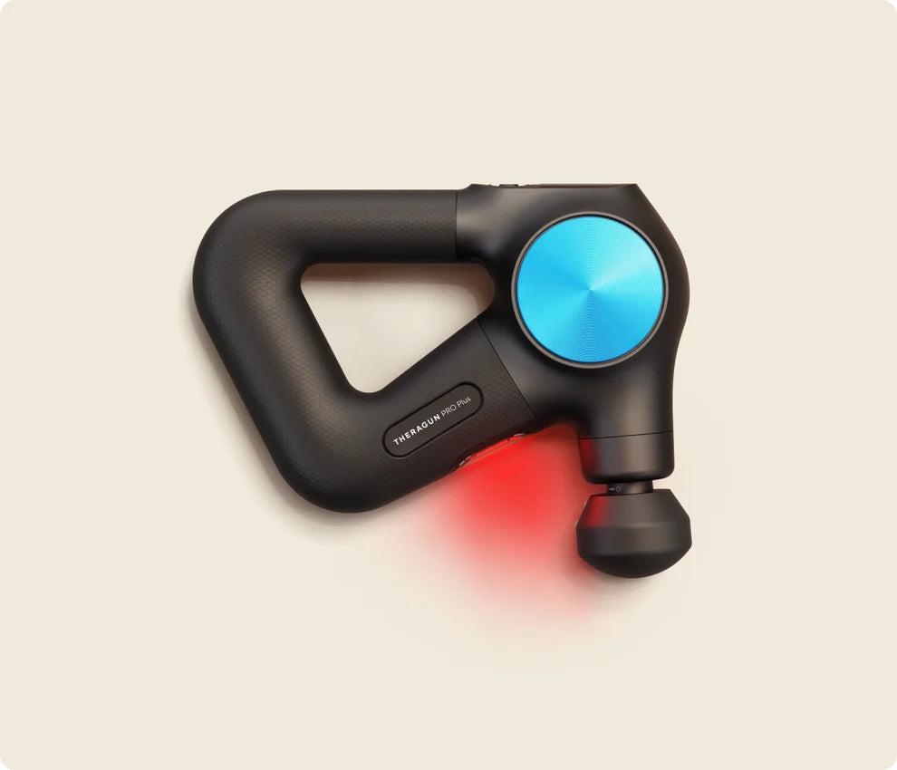 A black and blue Theragun PRO Plus massage gun with an ergonomic triangular handle and a round massage head, emitting red LED light, indicating heat therapy functionality.