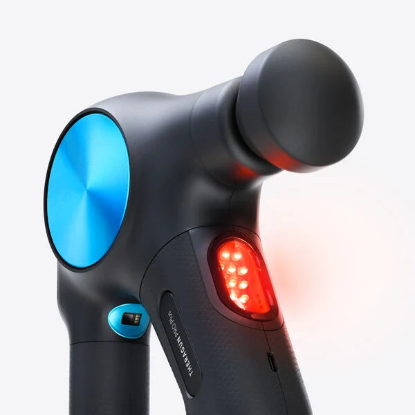 A close-up of a black and blue massage gun featuring a round attachment and an illuminated red LED panel, indicating heat therapy functionality. The device has a sleek, ergonomic design.