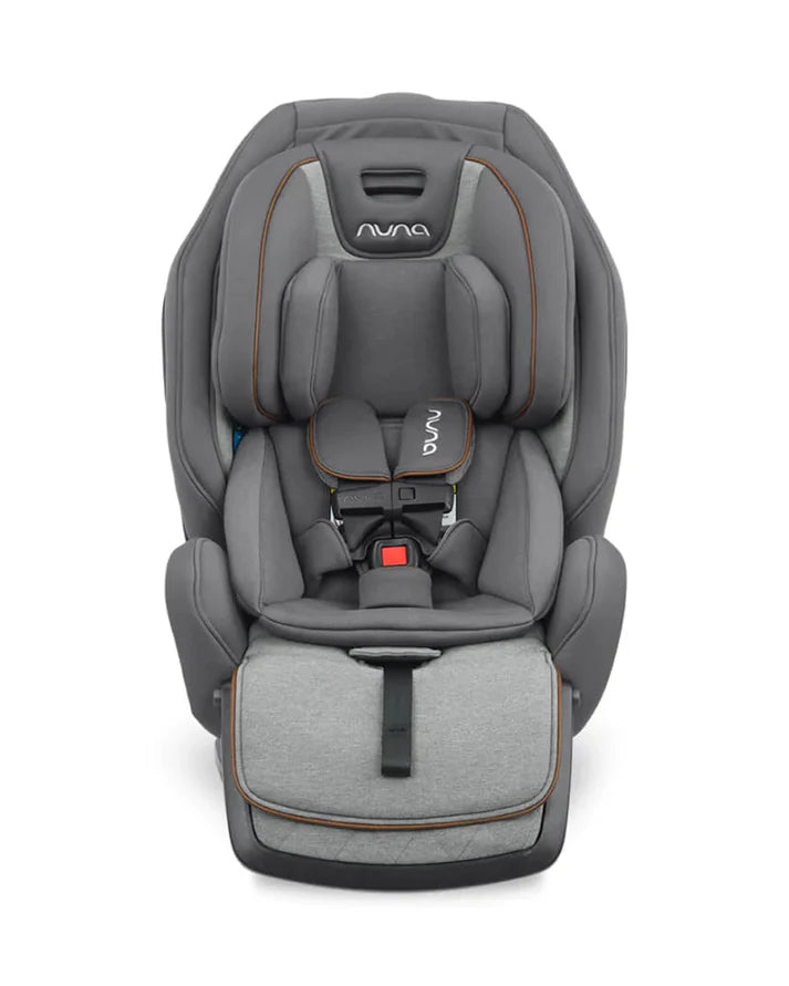 Front view of a grey Nuna child car seat featuring padded safety harnesses, adjustable headrest, and an extended quilted leg rest with a strap.