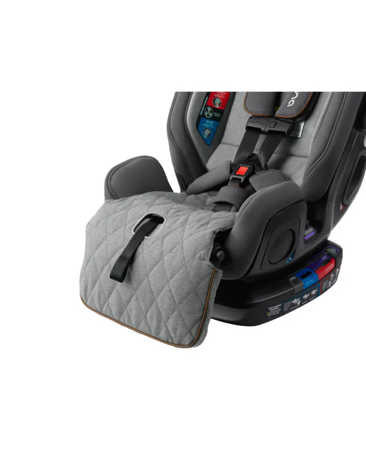 Close-up of a grey Nuna car seat showing a quilted leg rest extension with a strap, attached to the base labeled with color-coded installation guides.
