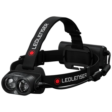 An LED Lenser headlamp featuring a black adjustable strap with the "LED LENSER" branding. The headlamp has a dual-lens light unit at the front and a battery pack at the back connected by a coiled cable. The design highlights the secure attachment, adjustable features, and powerful illumination capabilities of the headlamp.