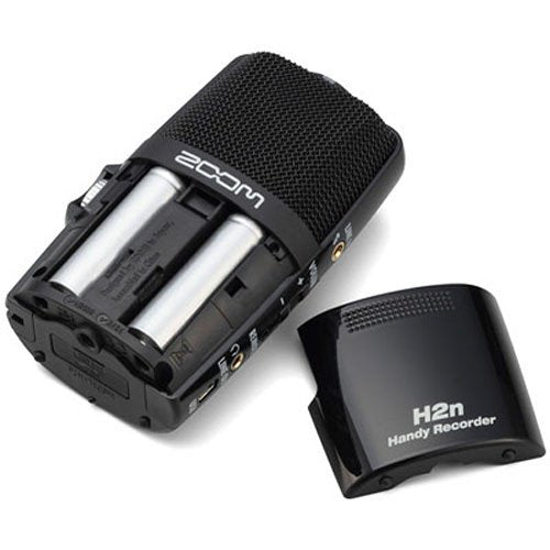 A Zoom H2n Handy Recorder with its battery cover removed, revealing two AA batteries inside the compartment.