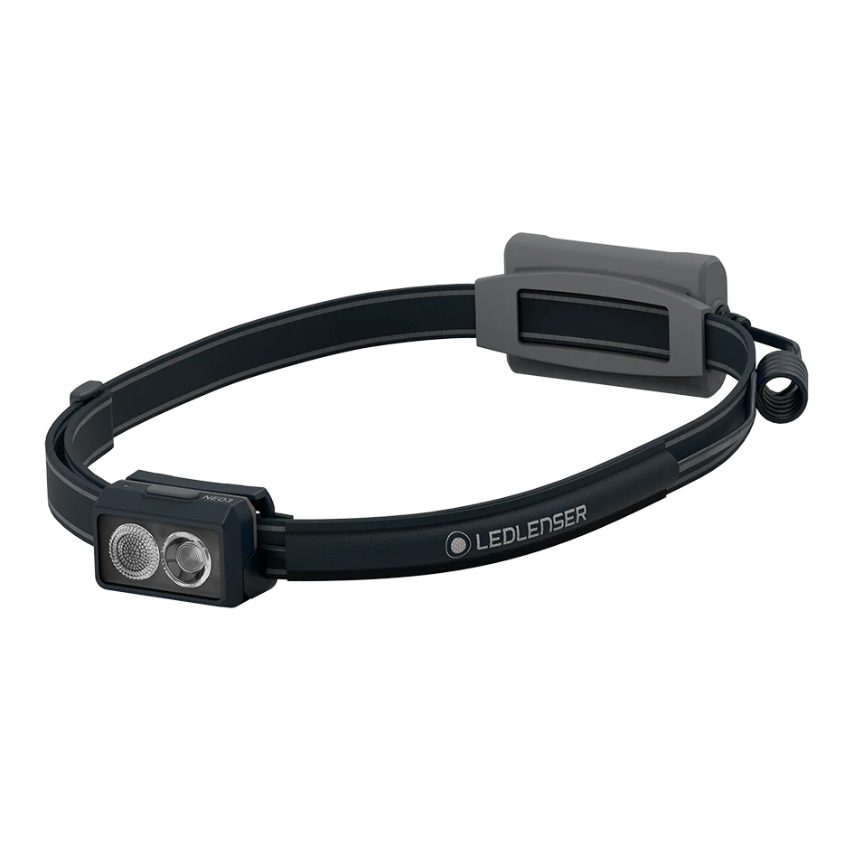 A black LED Lenser headlamp featuring dual LED lights in the front and a gray battery pack at the back. The headlamp has an adjustable strap with the LED Lenser logo printed on it. The design is sleek and functional, with the gray accents providing a modern touch.