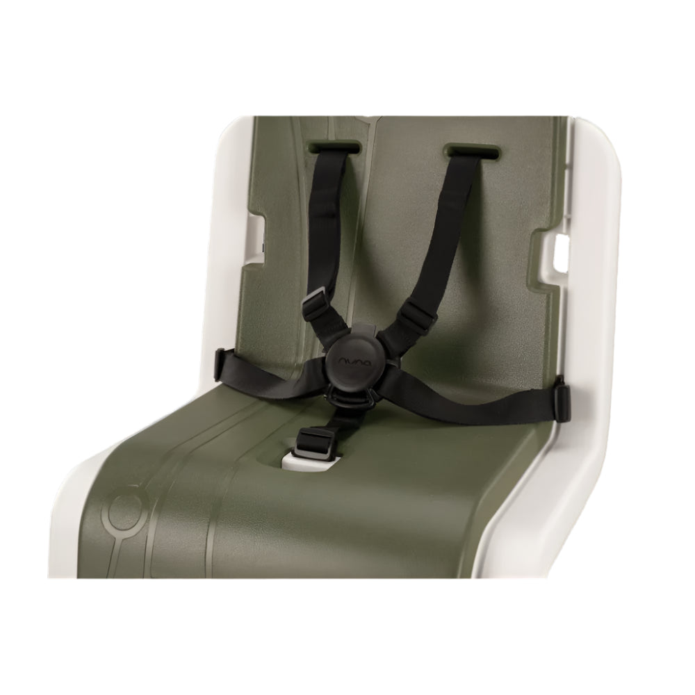 Close-up view of a Nuna child seat insert in green and white with a secure black five-point harness system, designed for safe and adjustable seating.