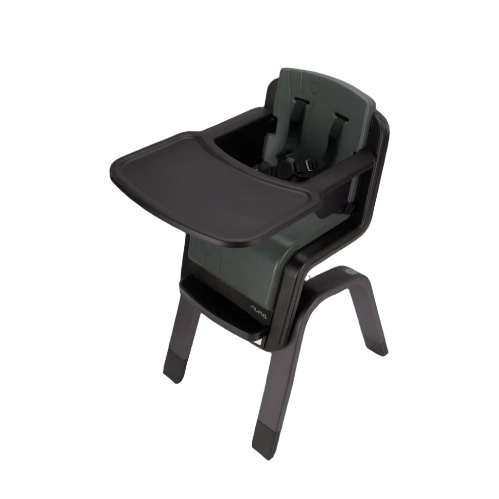 Angled view of a Nuna high chair in dark green and black with an attached tray and five-point harness, designed for secure and stylish toddler feeding.