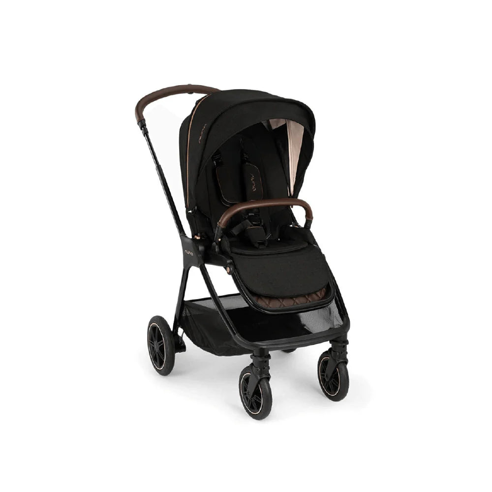 A woman is pushing a modern black stroller with a sleek frame and large canopy while walking along a city sidewalk.
