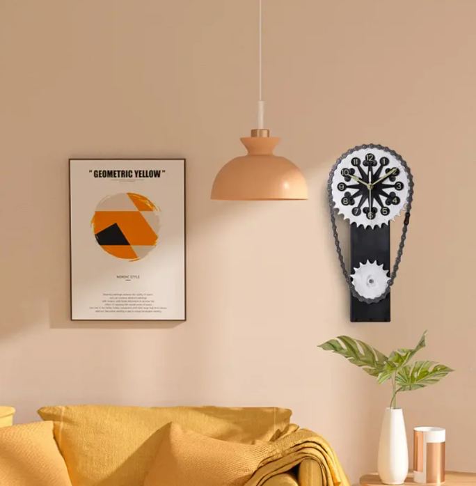 Modern living room setting with a gear-inspired clock mounted on a neutral wall, paired with minimalist decor, including a geometric art print, a peach-colored pendant lamp, a mustard yellow couch, and a potted green plant.