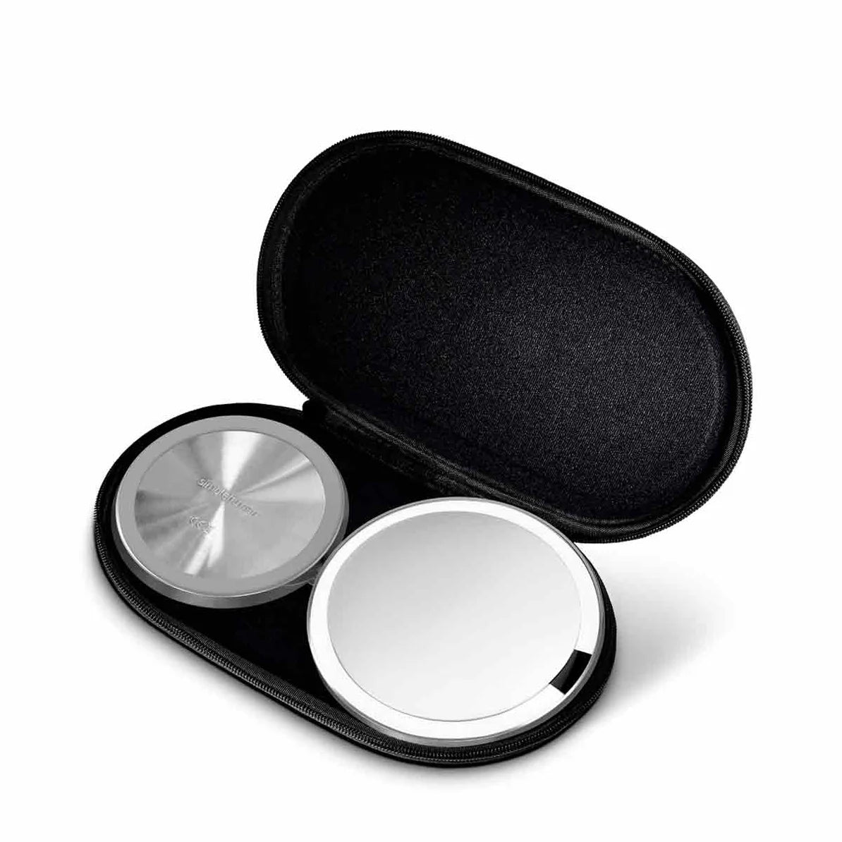 A black, hard-shell case is open to reveal two round objects inside. One of the objects has a brushed stainless steel finish with a circular pattern, and the other appears to be a compact mirror with a reflective surface. The interior of the case is padded, designed to securely hold the items, and the overall design is minimalist and functional, ideal for protection and portability. The case's sleek appearance complements the modern aesthetic of the items inside.