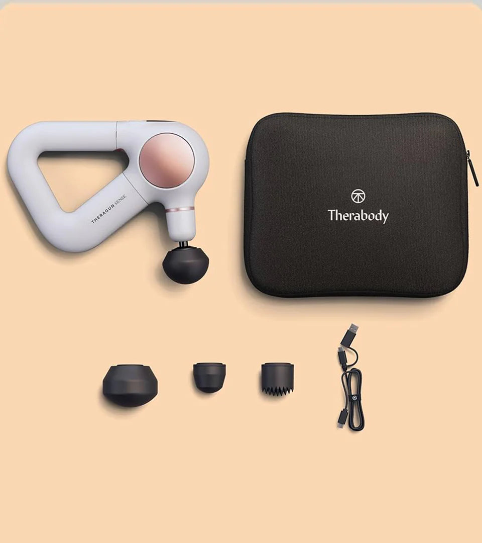 Theragun massage device set including the main device, multiple interchangeable attachments, a charging cable, and a branded carrying case, designed for versatile and portable muscle recovery solutions.