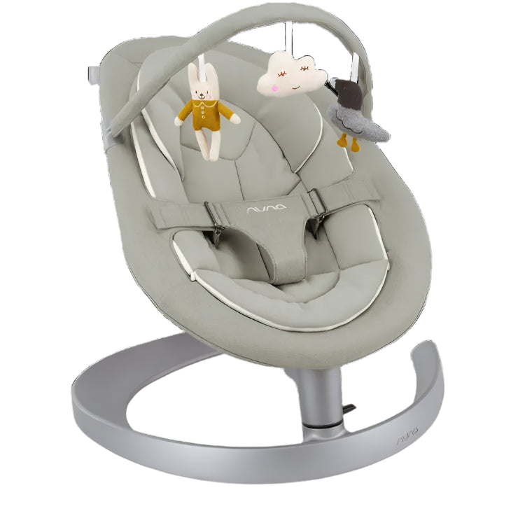 A cushioned Nuna baby rocker in soft beige with a toy bar featuring plush hanging toys—a bunny, cloud, and bird—for soothing and engaging infants.