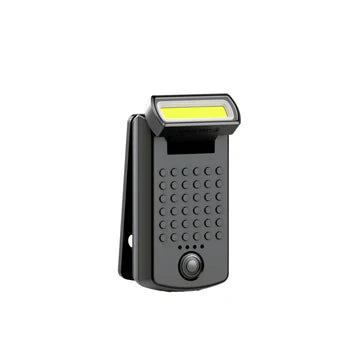 A compact black LED clip light with a rectangular design. It features a long, narrow LED strip at the top, a textured grip area with raised dots in the middle, and a power button near the bottom. The clip on the back allows for easy attachment to various surfaces.