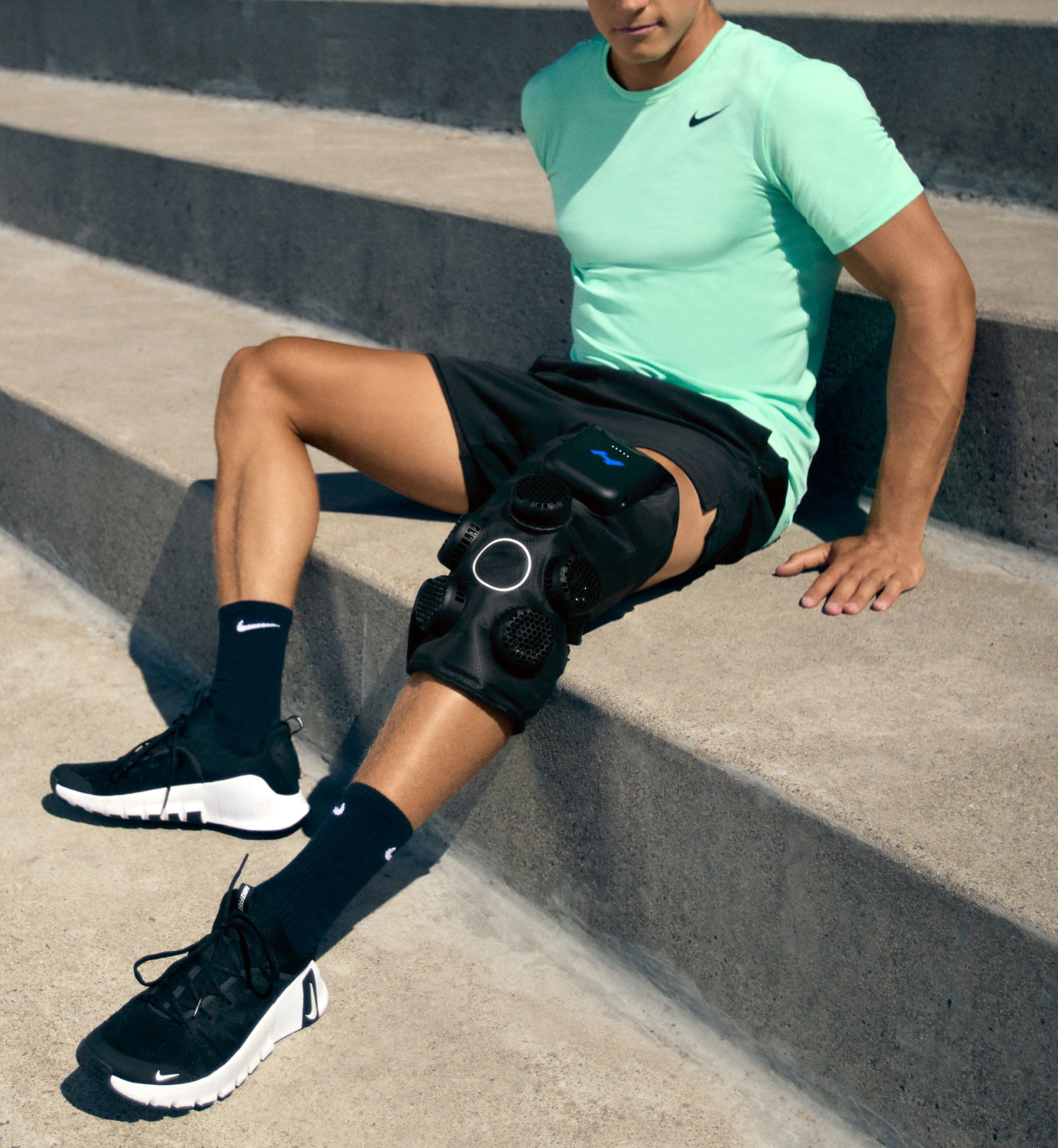 Person wearing the Hyperice Contrast 2 Knee device on outdoor steps