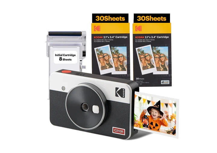 An image displaying a **Kodak C210R instant camera bundle**, which includes the camera, photo cartridges, an initial cartridge pack, a leather carrying case, photo albums, decorative clips, and accessories for capturing and displaying instant memories.
