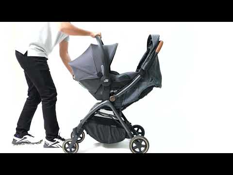 Side view of a Britax Gravity II stroller with a Baby Safe Core infant car seat attached, showing installation in progress by a person standing beside it.