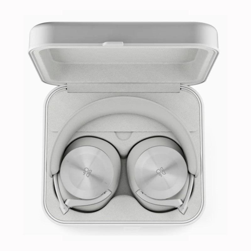 This image displays **Bang & Olufsen over-ear headphones** in **light gray** or **silver**, carefully stored in their **matching carrying case**. The headphones are neatly folded, with the ear cups laying flat, highlighting their **sleek and modern design**. The carrying case has a **soft fabric interior** that matches the light gray tone of the headphones, providing a secure and premium storage solution for travel or safekeeping. The case and the headphones reflect **Bang & Olufsen's attention to luxury an
