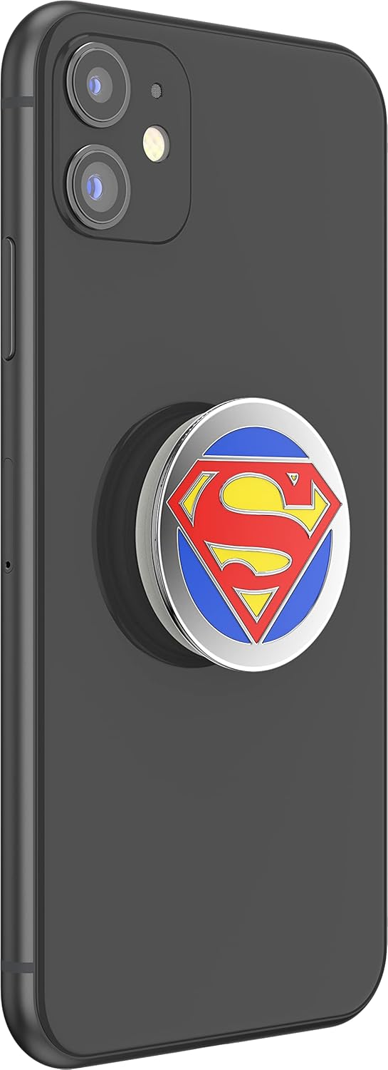  A black smartphone with a PopSockets Enamel Swappable Grip featuring the Superman logo attached to the back. The grip displays the iconic Superman "S" shield in red and yellow on a blue background, encased in a shiny metal border. The design adds a pop of color and superhero flair to the phone, providing both style and functionality with its swappable and expandable features.