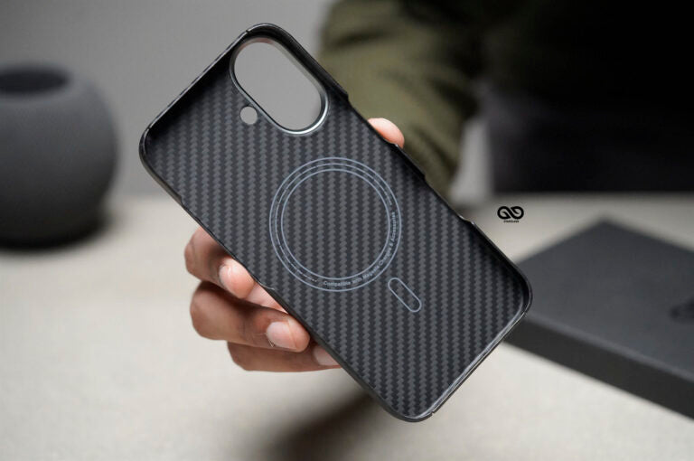 This image displays a close-up of a carbon fiber-textured phone case, likely compatible with MagSafe or similar magnetic accessories. The inner side of the case features a circular design, indicating the magnetic alignment for MagSafe compatibility, which allows for seamless attachment of chargers or other accessories. The case includes precise cutouts for the camera, flash, and possibly a microphone, designed to fit snugly around a smartphone model with a dual-camera setup. The carbon fiber pattern adds a 