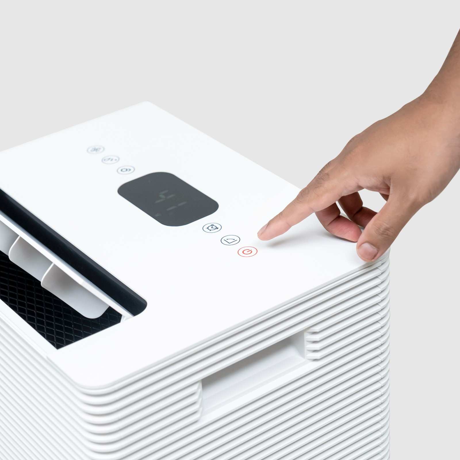 Close-up view of a person pressing the power button on the digital control panel of the White Westinghouse Dehumidifier AWHD50L. The top section also features a built-in handle and air vents. The sleek white design is suitable for maintaining optimal humidity levels in residential and commercial spaces.