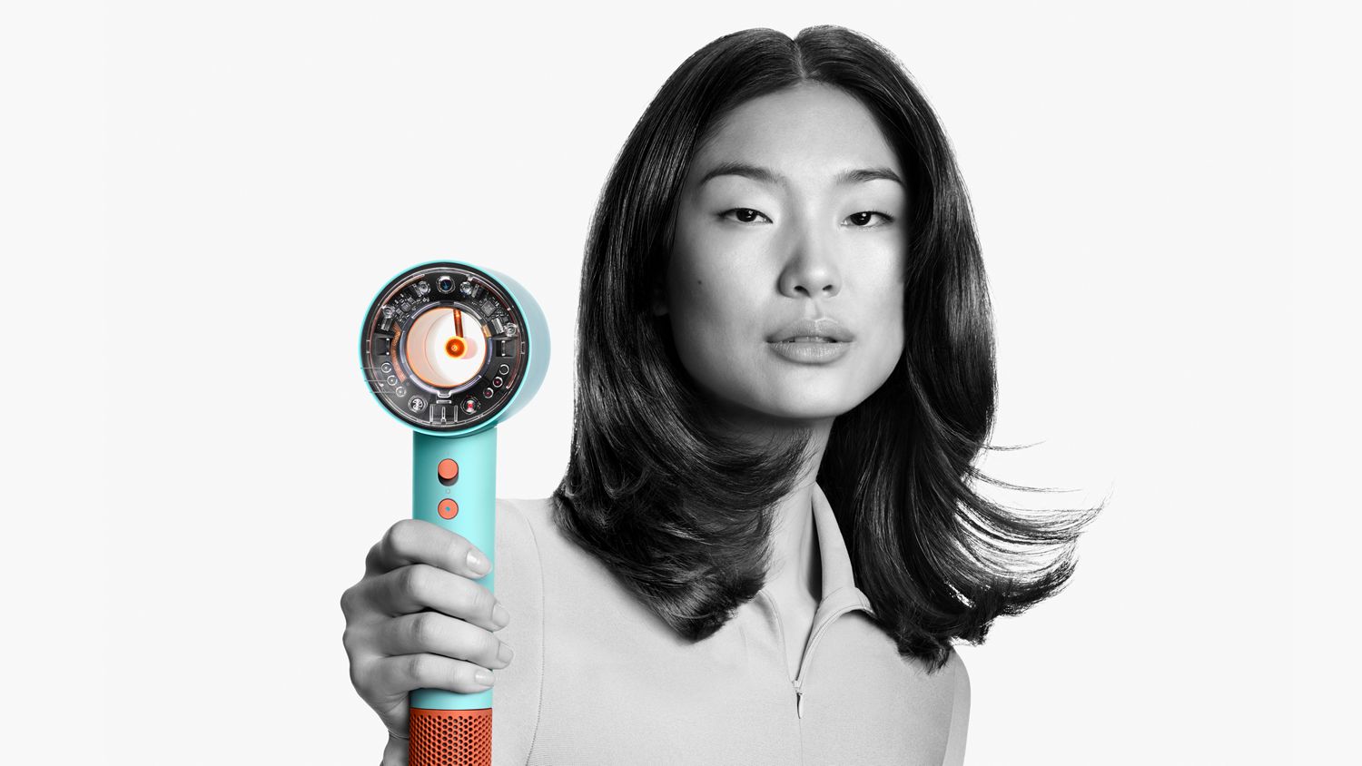 A woman with smooth, voluminous hair holds a futuristic turquoise hair dryer featuring an exposed, intricate inner mechanism. The image is in monochrome with the hair dryer standing out in vibrant color.