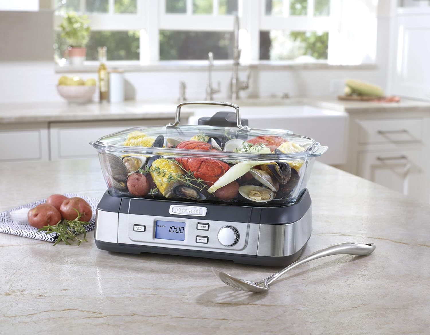Cuisinart STM-1000 glass steamer on a kitchen counter steaming vegetables and potatoes