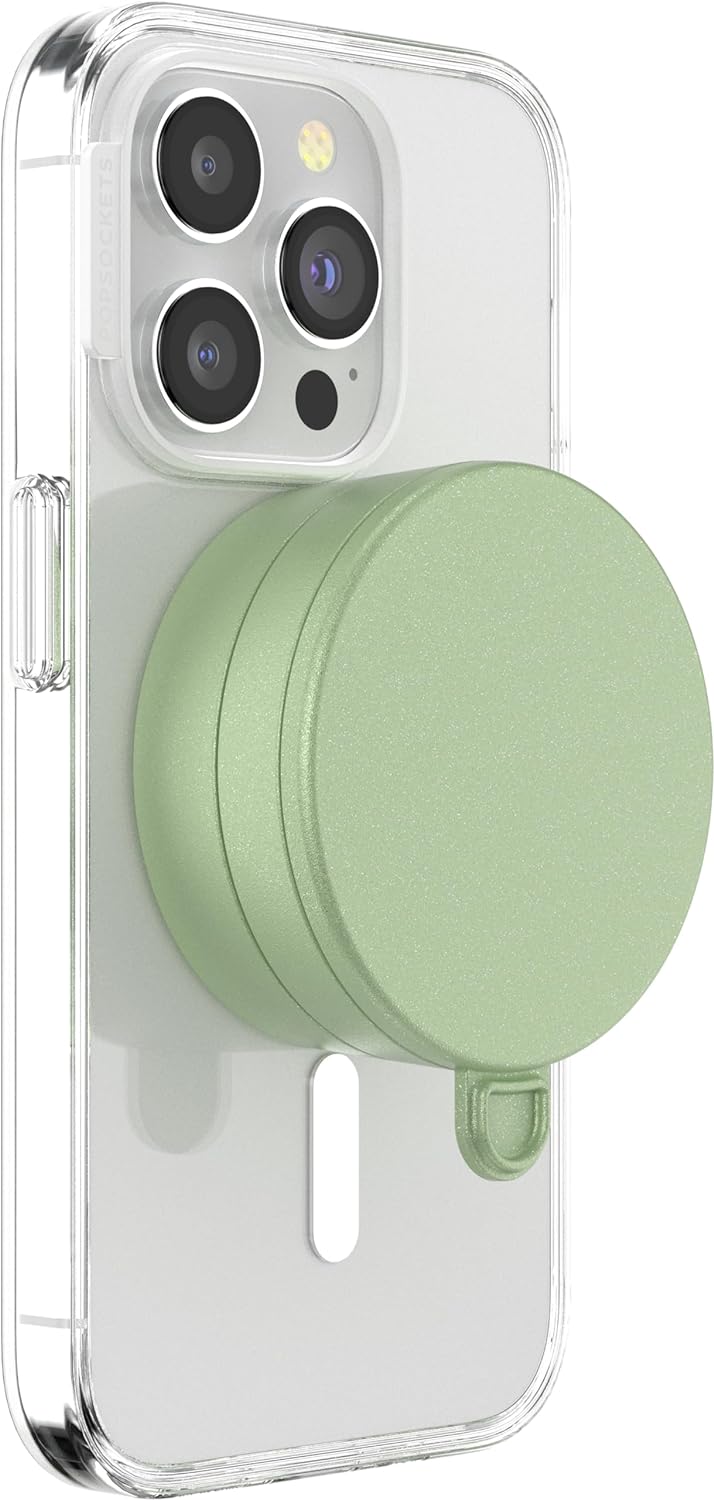 A smartphone with a clear case is shown with an eucalyptus green PopSockets Suction Mount for MagSafe attached to its back. The mount is securely positioned in the center of the phone's back, demonstrating its compatibility and ease of use with MagSafe technology. The phone's camera lenses are visible at the top, emphasizing the mount's unobtrusive and stylish design.