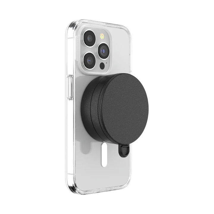 A smartphone with a clear case is shown with a black PopSockets Suction Mount for MagSafe attached to its back. The mount is securely positioned in the center of the phone's back, demonstrating its compatibility and ease of use with MagSafe technology. The phone's camera lenses are visible at the top, emphasizing the mount's unobtrusive design.