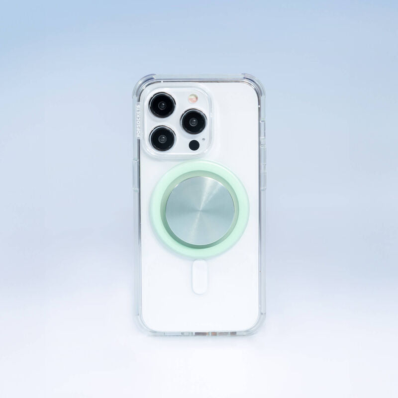  A smartphone with a clear case PopGrip for MagSafe in honey dew color attached to its back. The PopGrip features a glossy, slightly reflective soft green surface, positioned centrally on the phone's back. The phone's camera lenses are visible at the top, highlighting the PopGrip's sleek and modern design, which complements the phone's aesthetics while providing a functional grip.