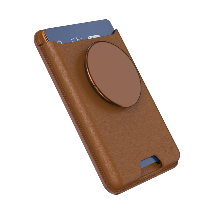 PopSockets MagSafe Softgoods PopWallet in Cognac. The wallet, designed for holding cards, is shown at an angle with a card partially inserted, showcasing its functionality. The circular PopSocket attached to the wallet is in the same cognac color. The material appears to be a soft, leather-like texture with clean stitching along the edges. The PopSockets logo is subtly embossed near the bottom right corner.