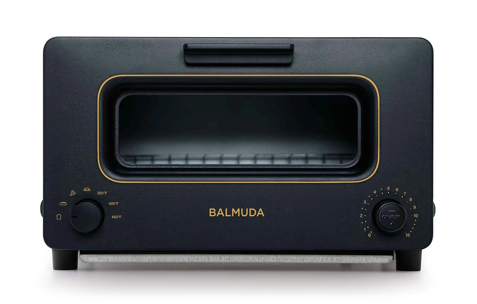  The image shows a front view of the Balmuda toaster in a sleek matte black finish. The toaster features a large rectangular viewing window bordered by a subtle gold accent. Below the window, the brand name "BALMUDA" is centered in gold lettering.