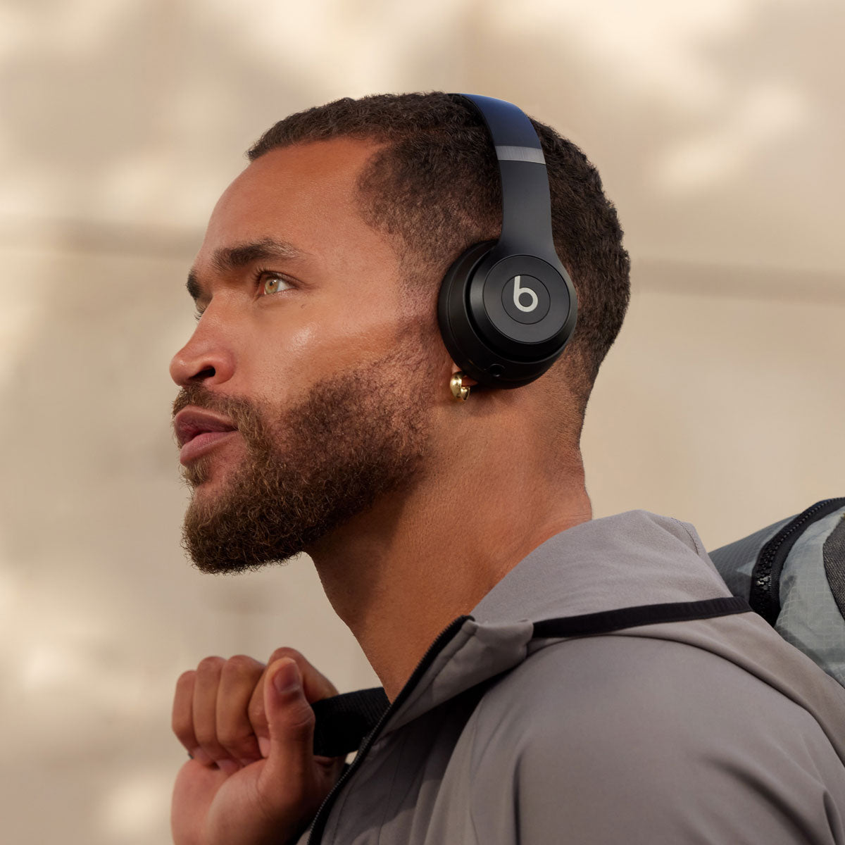 "Man wearing black Beats by Dre wireless over-ear headphones in an outdoor setting, highlighting sleek design and premium sound quality."