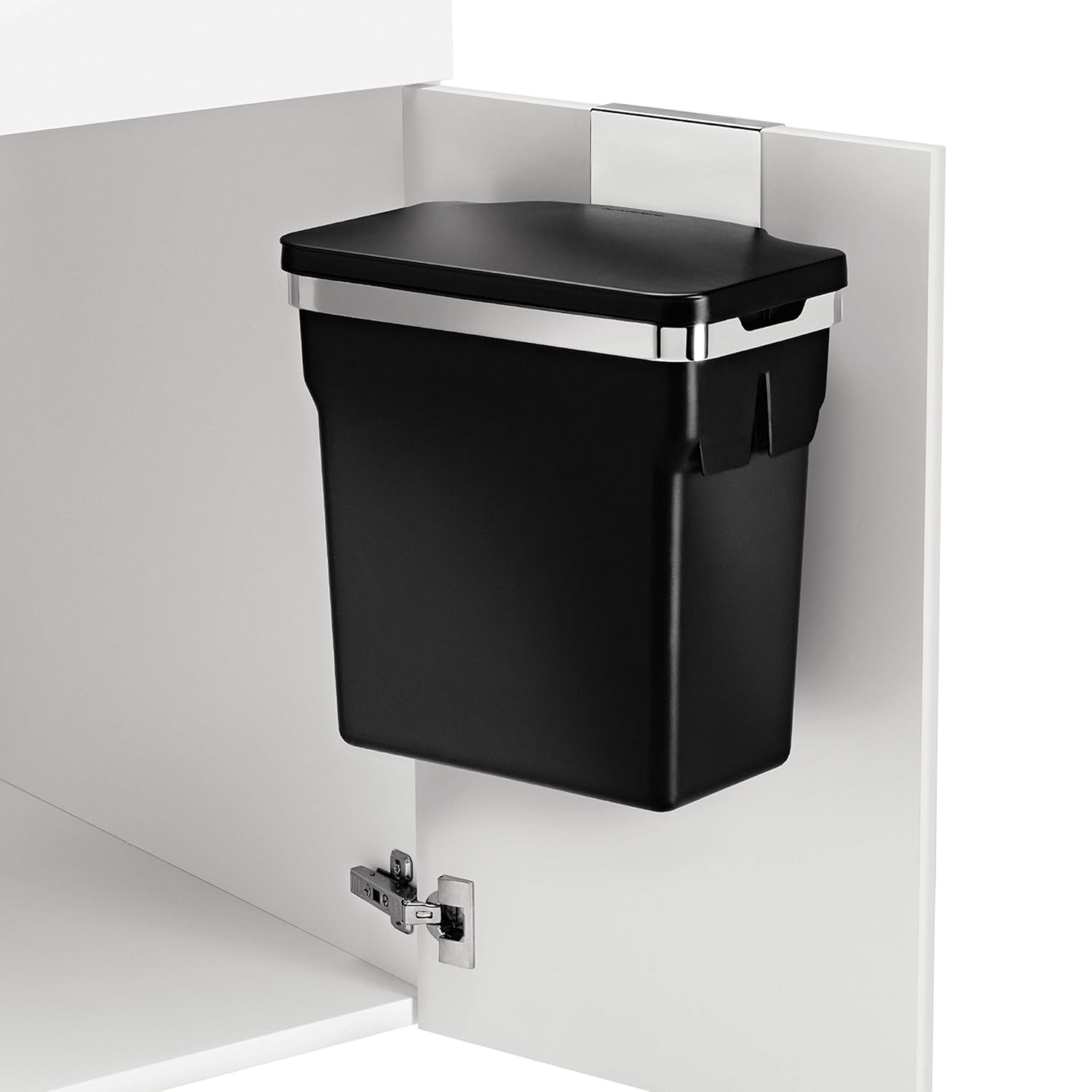 This image shows a black trash bin mounted on the inside of a white cabinet door. The bin features a streamlined, space-saving design, secured with a silver metal bracket that allows it to hang neatly, keeping the floor space free. This setup is ideal for keeping waste concealed and the kitchen or workspace clean and clutter-free.