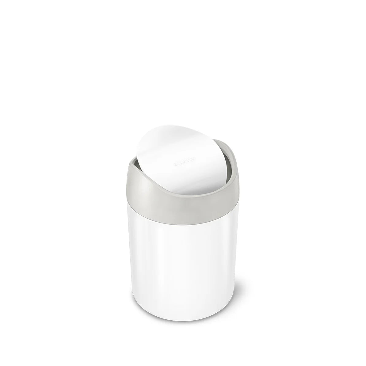 The image shows a Simplehuman mini round trash can with a white body and a matte gray swing lid. The lid is partially open, allowing a view of the interior. The trash can is compact and has a cylindrical shape, making it ideal for small spaces like bathroom countertops, vanities, or desks. The white and gray color combination gives the trash can a clean and modern appearance. The swing lid is designed for easy and hygienic disposal of small items, automatically closing after use. This design emphasizes both