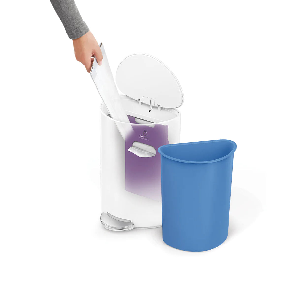 The image shows a person removing a white plastic bag from a white trash can. The trash can has a foot pedal for hands-free operation and an inner blue bin that has been taken out. The inner bin is designed to hold the trash bag, making it easy to remove and replace the bag. The design appears sleek and functional, suggesting that the product is made for easy waste management with a focus on hygiene and convenience.