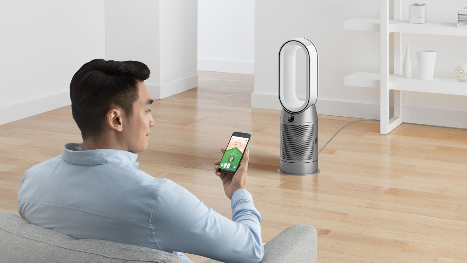 Man using a smart air purifier, adjusting settings via a mobile app, demonstrating seamless control and smart home integration for optimized air quality.