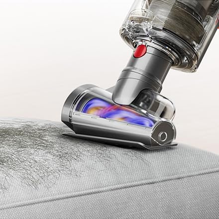 Cordless vacuum cleaner removing pet hair from upholstery, demonstrating powerful suction and specialized attachment for pet owners.