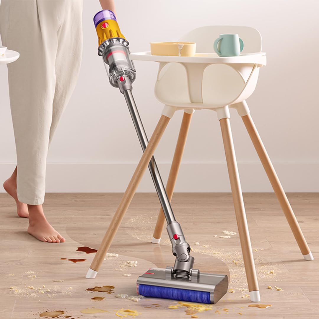 Cordless vacuum cleaner tackling food spills and debris under a high chair, highlighting efficient cleaning for households with children.