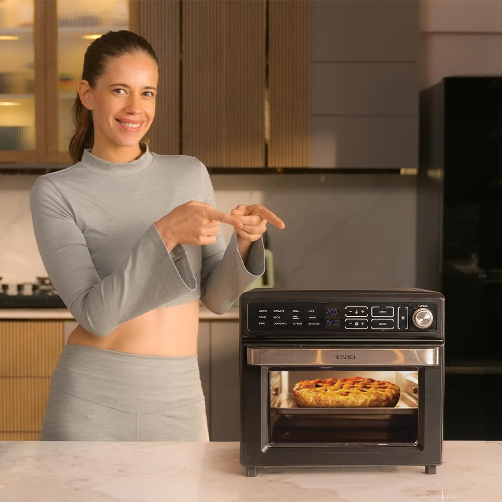 Woman presenting a 25L air fryer with convection, showing a freshly baked pie inside.