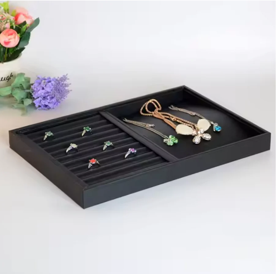 Jewelry display tray with ring slots and a separate section for necklaces and pendants.