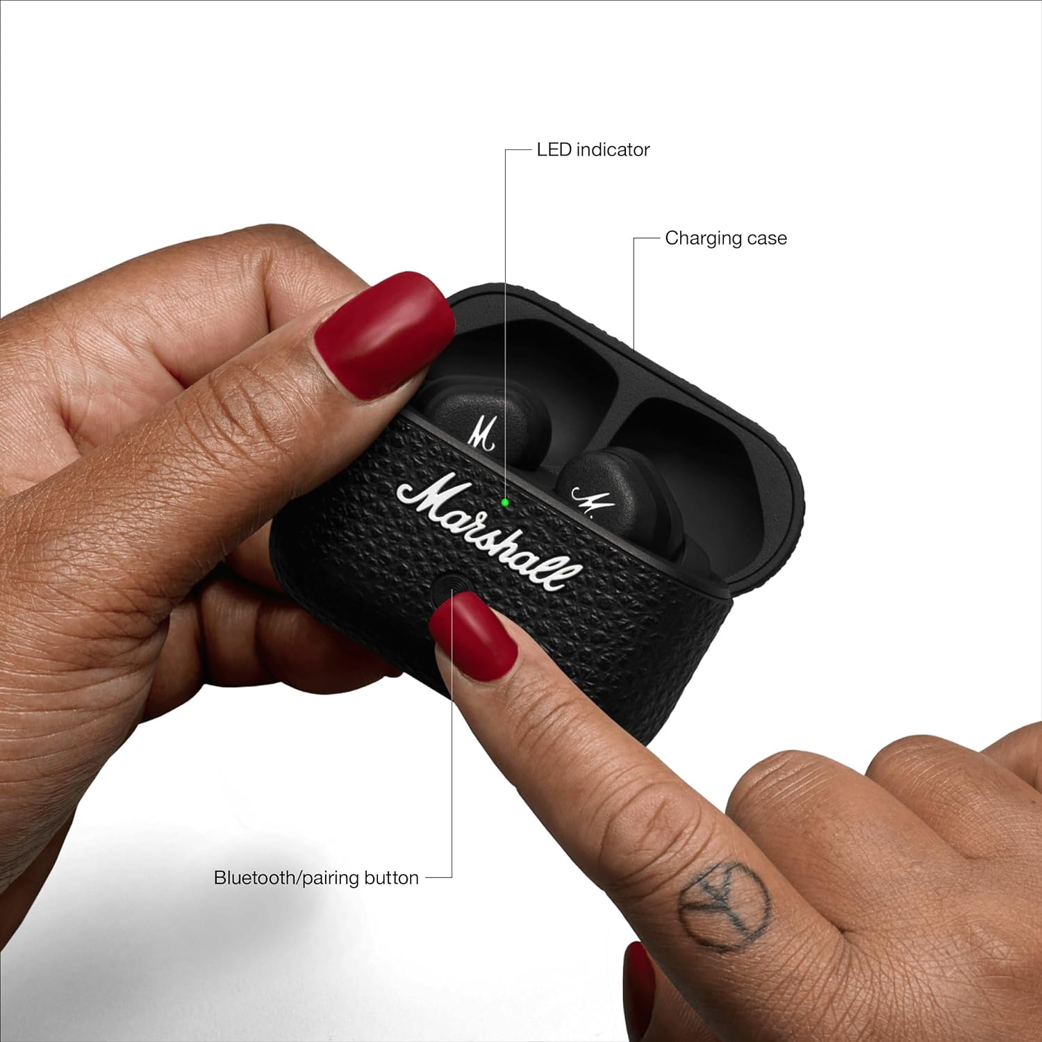 "Hands holding the Marshall Motif II A.N.C. True Wireless earbuds in the charging case, highlighting Bluetooth pairing button and LED indicator for easy connectivity."