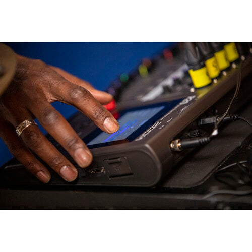 A close-up of a hand interacting with the touch screen of the Zoom R20 audio mixer and recorder. The device features multiple input channels with yellow-marked cables connected, highlighting its multi-channel capabilities. The image focuses on the user's hand, showcasing the tactile and interactive nature of the equipment's interface.